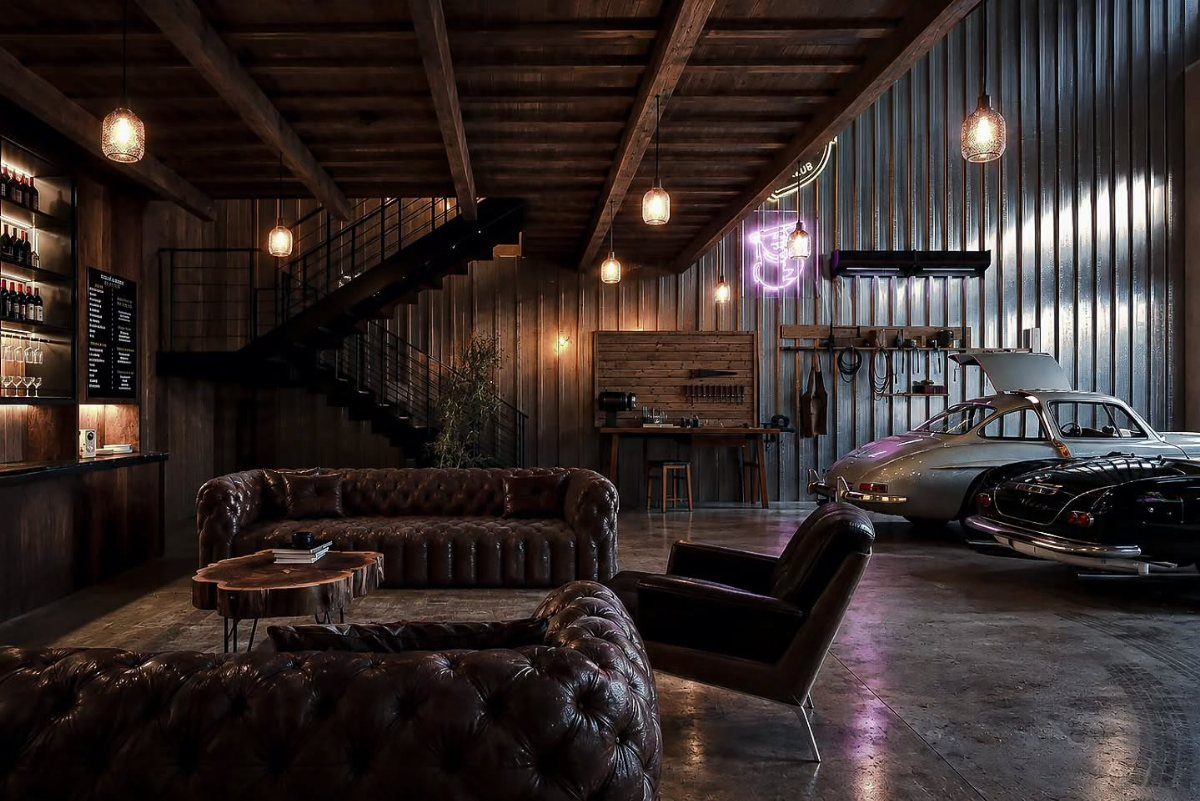 Leather sofas and a vintage car sit in an industrial lounge with metal walls.