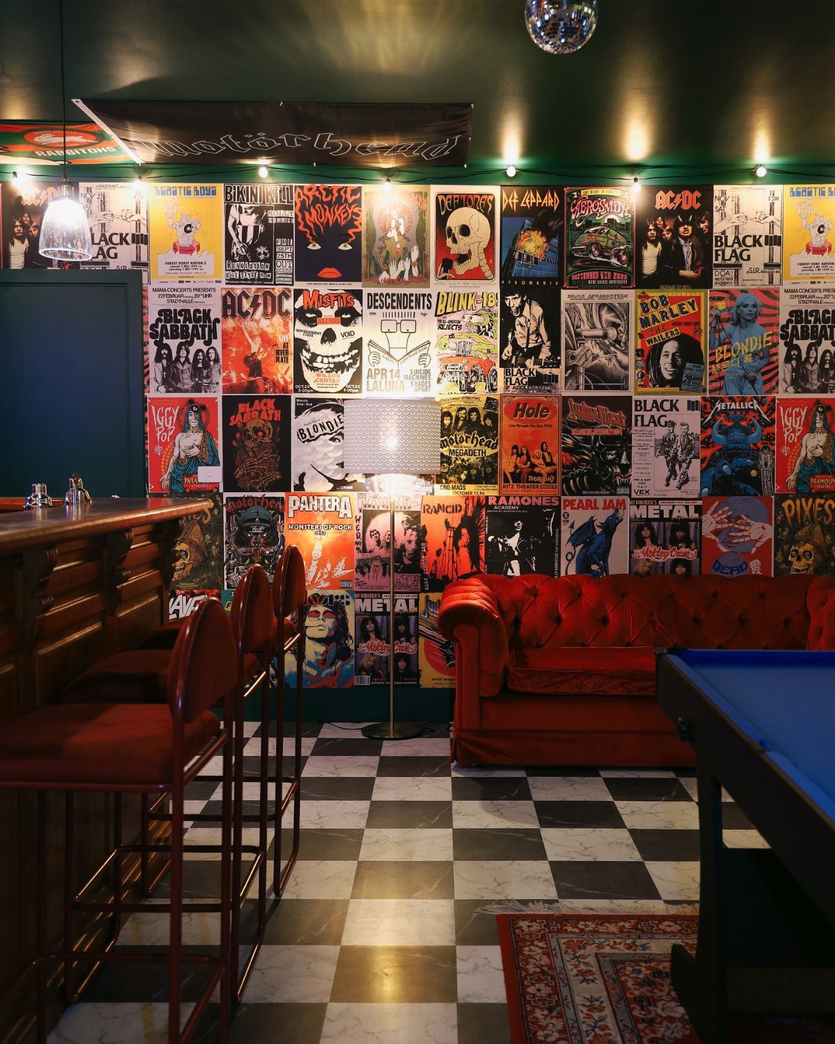 A wall covered in various colorful rock music posters in a bar setting.