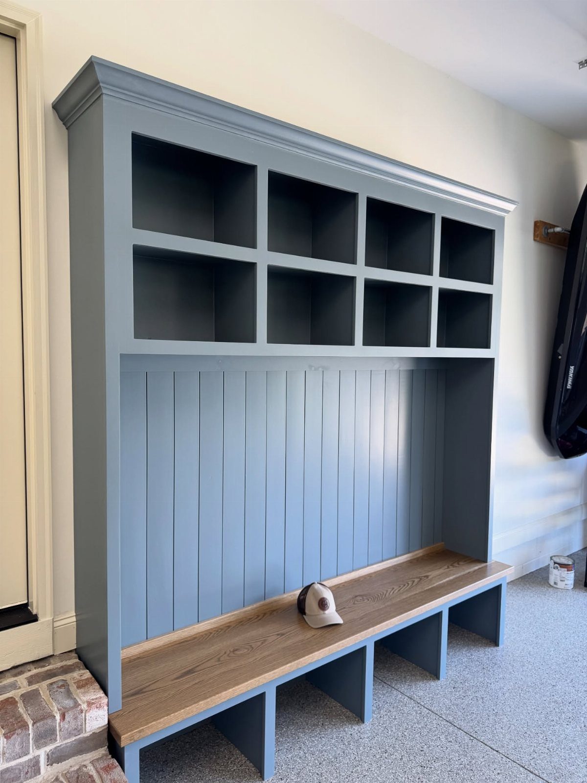 A blue built-in mudroom unit with cubbies and a long wooden bench in a garage.