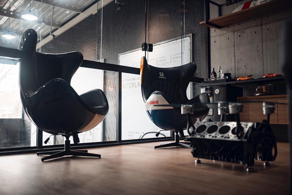 10 Garage Hangout Ideas for Comfortable Seating, Lighting, and More 8 Two black modern lounge chairs positioned in a room with large glass windows and wooden floors.