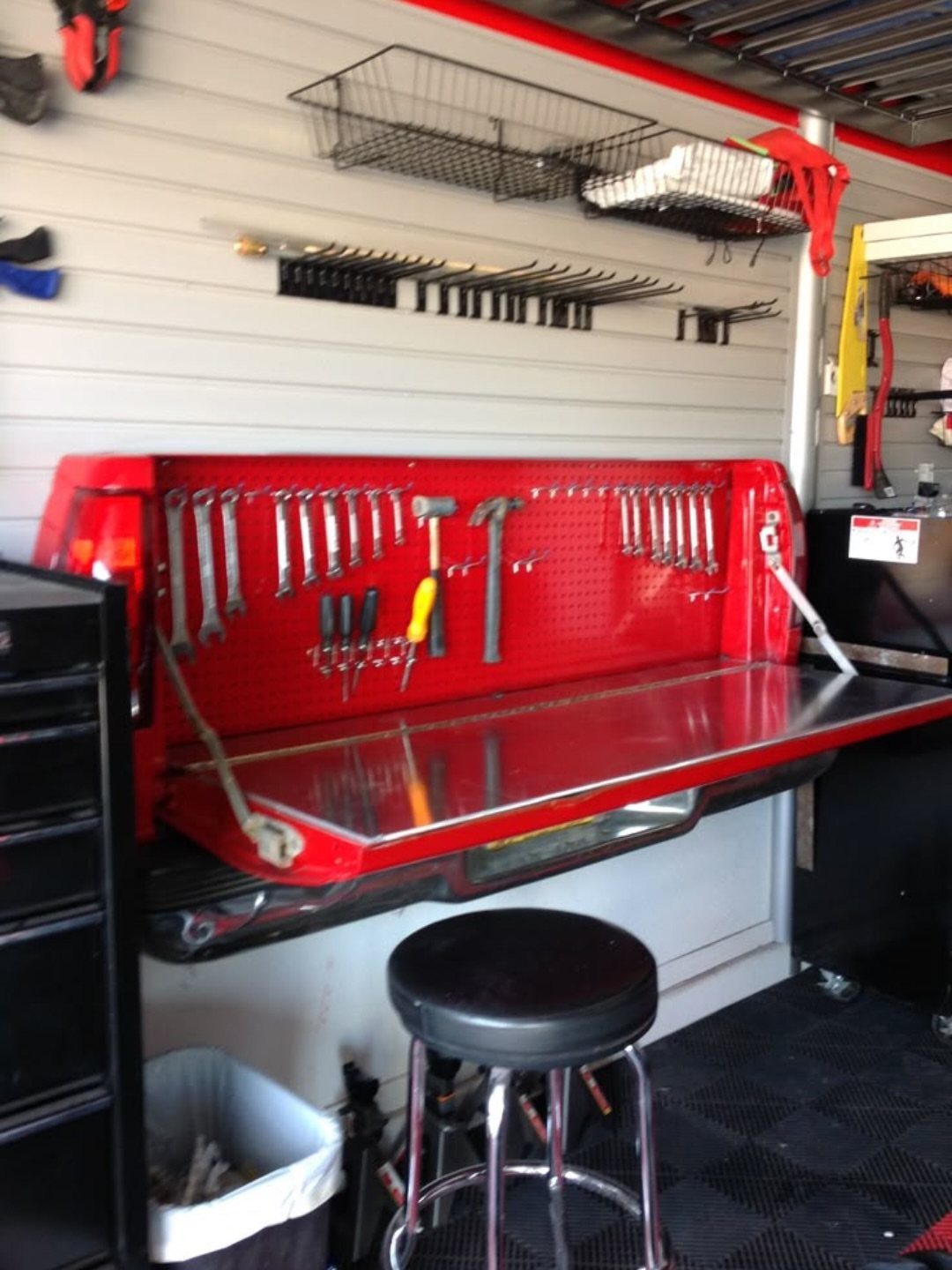 10 Garage Hangout Ideas for Comfortable Seating, Lighting, and More 5 Red workbench with metal top and organized hand tools on a pegboard in a garage.