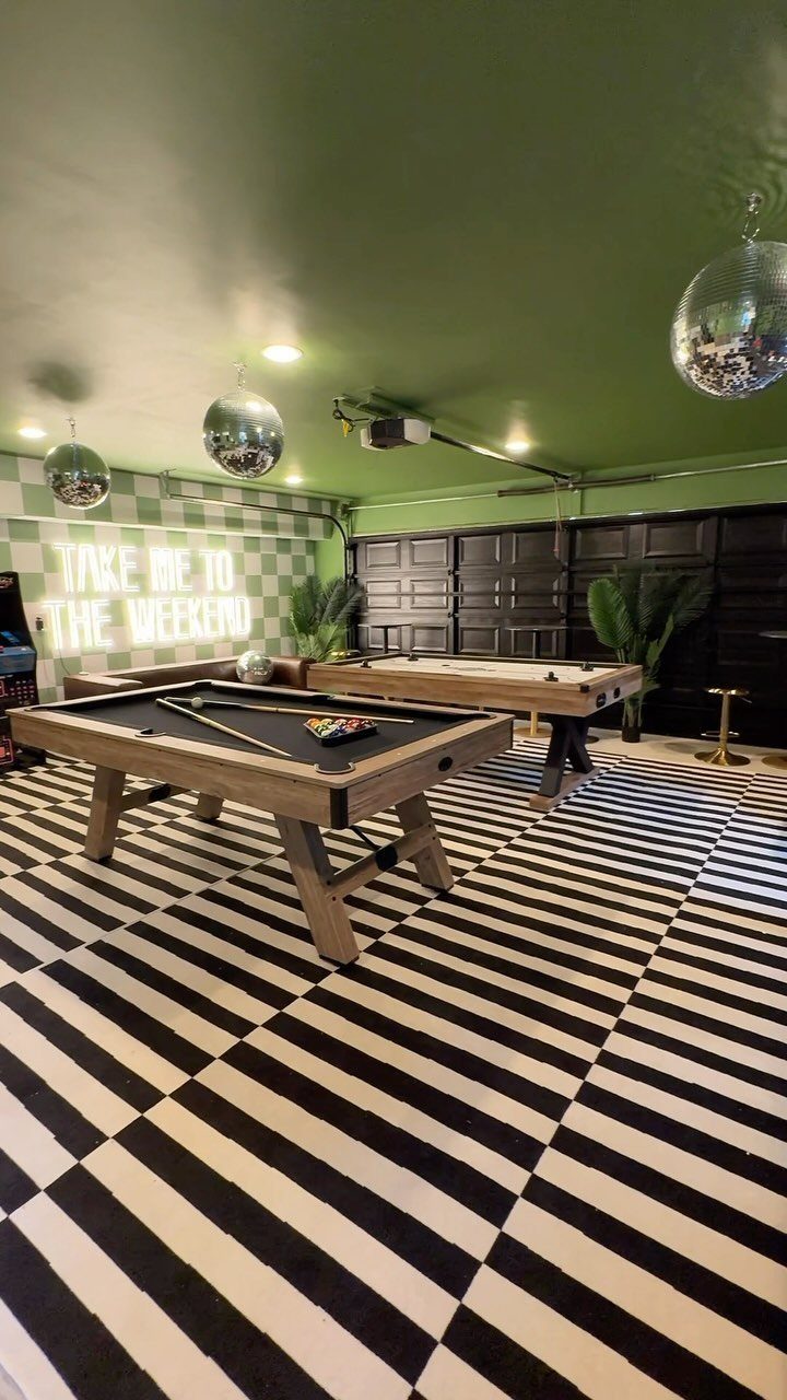 10 Garage Hangout Ideas for Comfortable Seating, Lighting, and More 2 Two pool tables sit on a black and white checkered floor in a green garage game room.