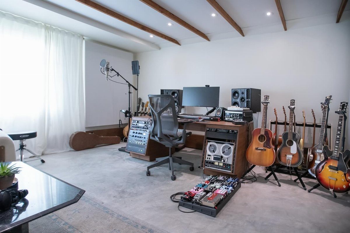 10 Garage Hangout Ideas for Comfortable Seating, Lighting, and More 4 A professional music studio with guitars, recording equipment, a microphone, and a computer workstation.
