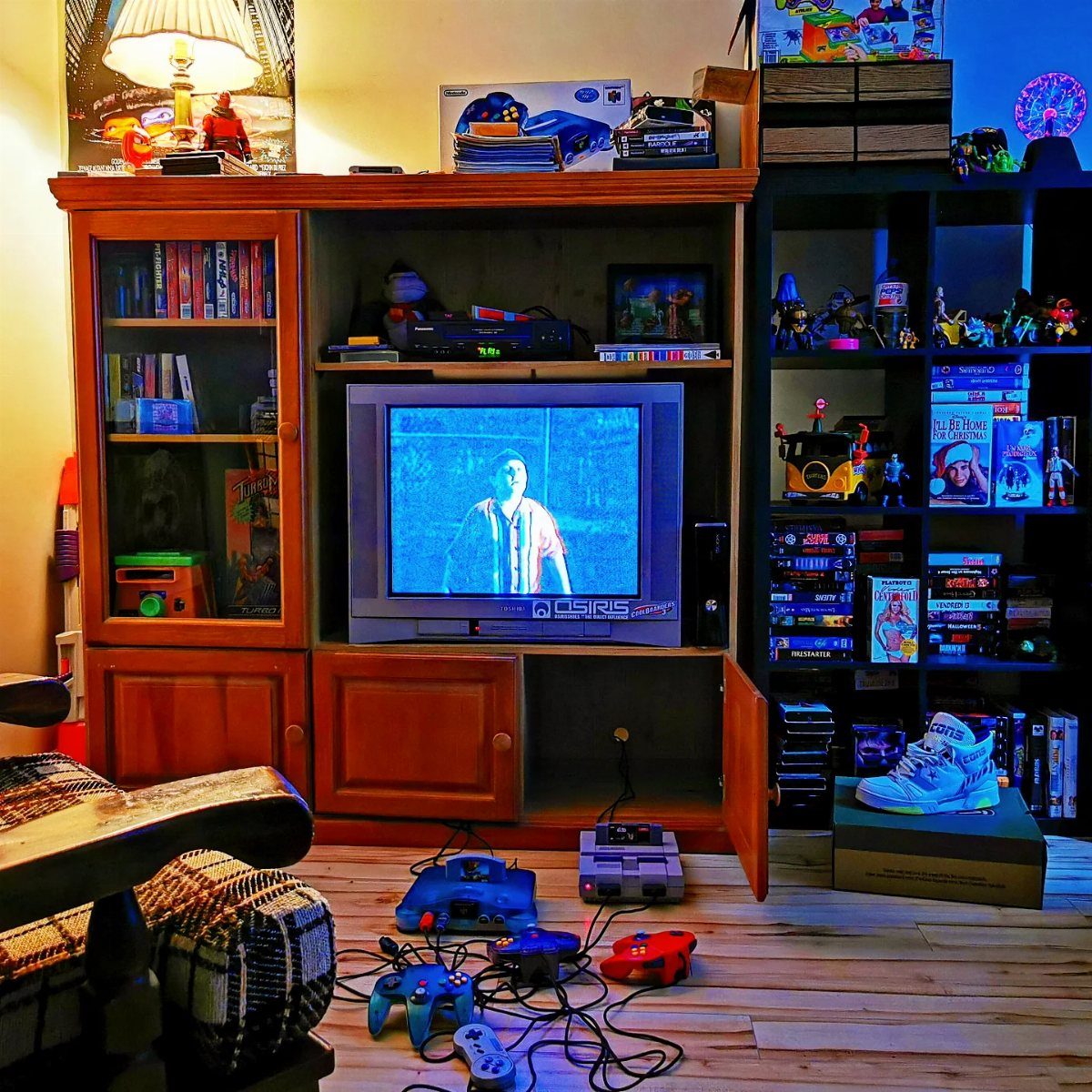 10 Garage Hangout Ideas for Comfortable Seating, Lighting, and More 6 Retro gaming setup with a CRT television, various consoles, and controllers on a wooden floor.
