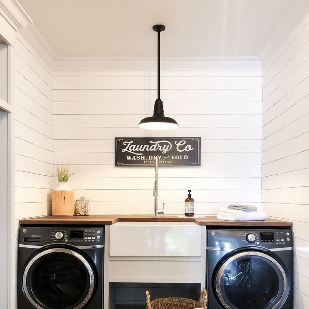 11 Garage Laundry Room Ideas for Storage, Style and Smart Layouts 5 Black pendant light hanging above a white laundry room sink and washing machines.