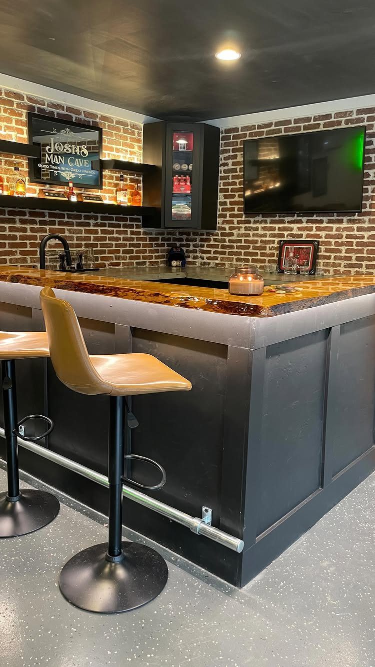 A modern home wet bar with a wooden counter, brick walls, and tan bar stools.