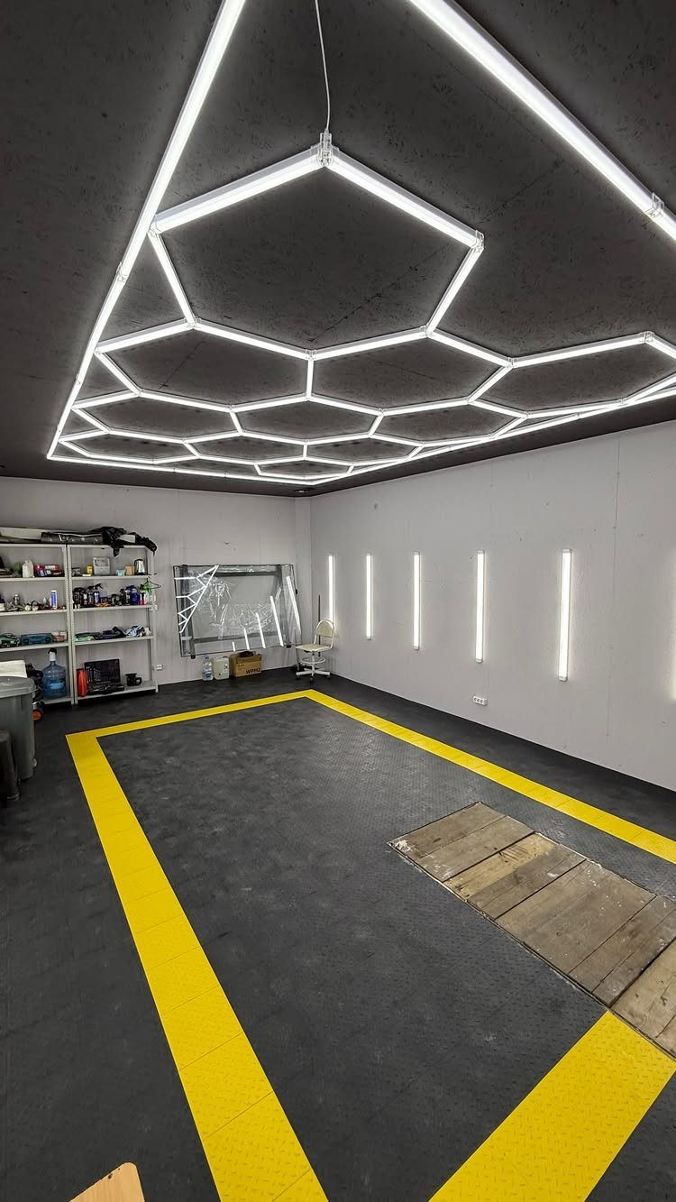 Geometric honeycomb LED lights on a dark ceiling above a modern garage floor.