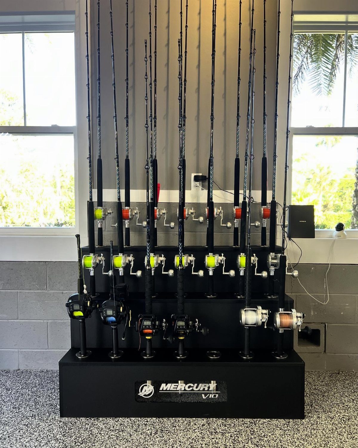 Multiple fishing rods with reels organized vertically in a black tiered storage rack.
