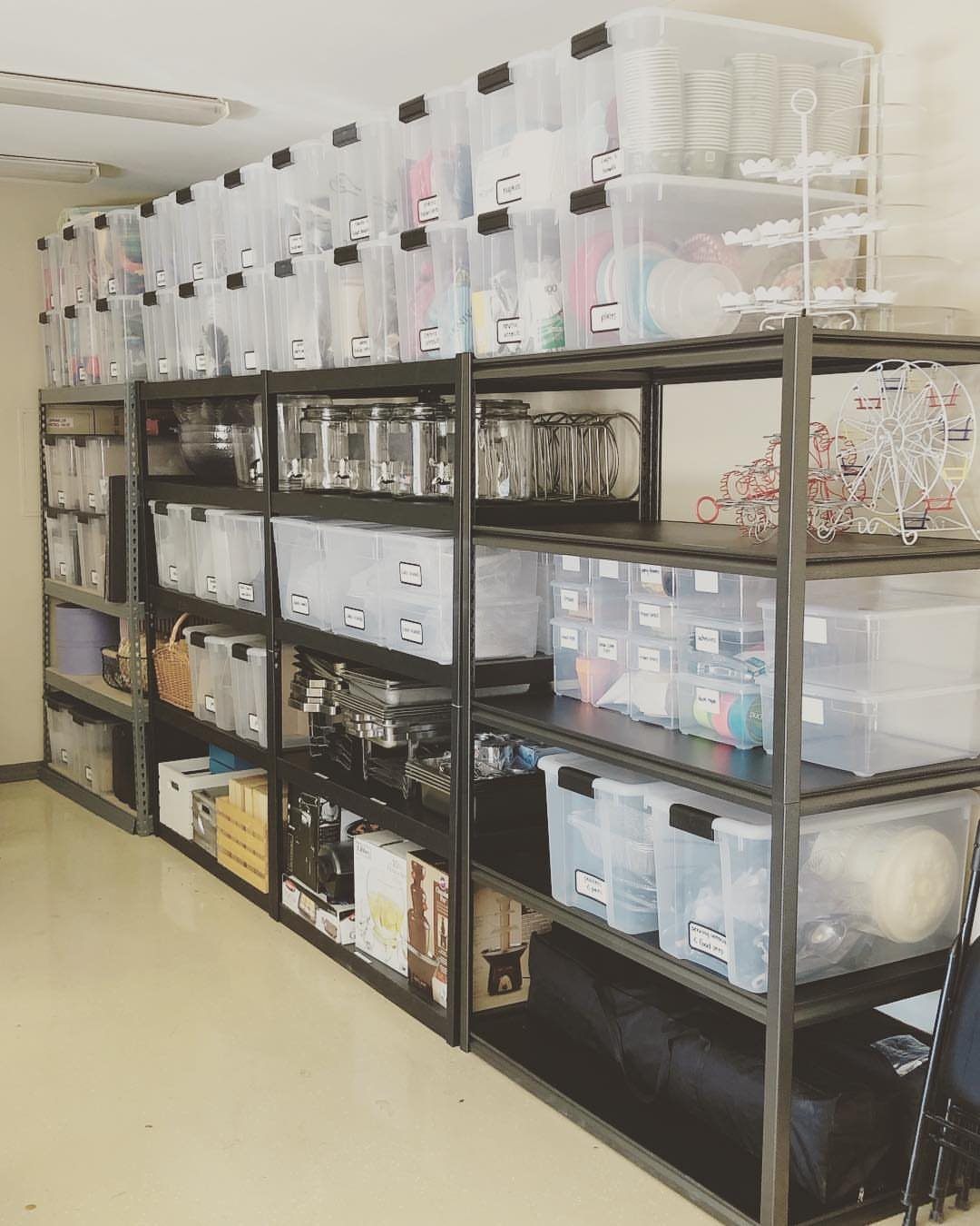 Clear plastic storage bins organized on long metal shelving units in a garage.