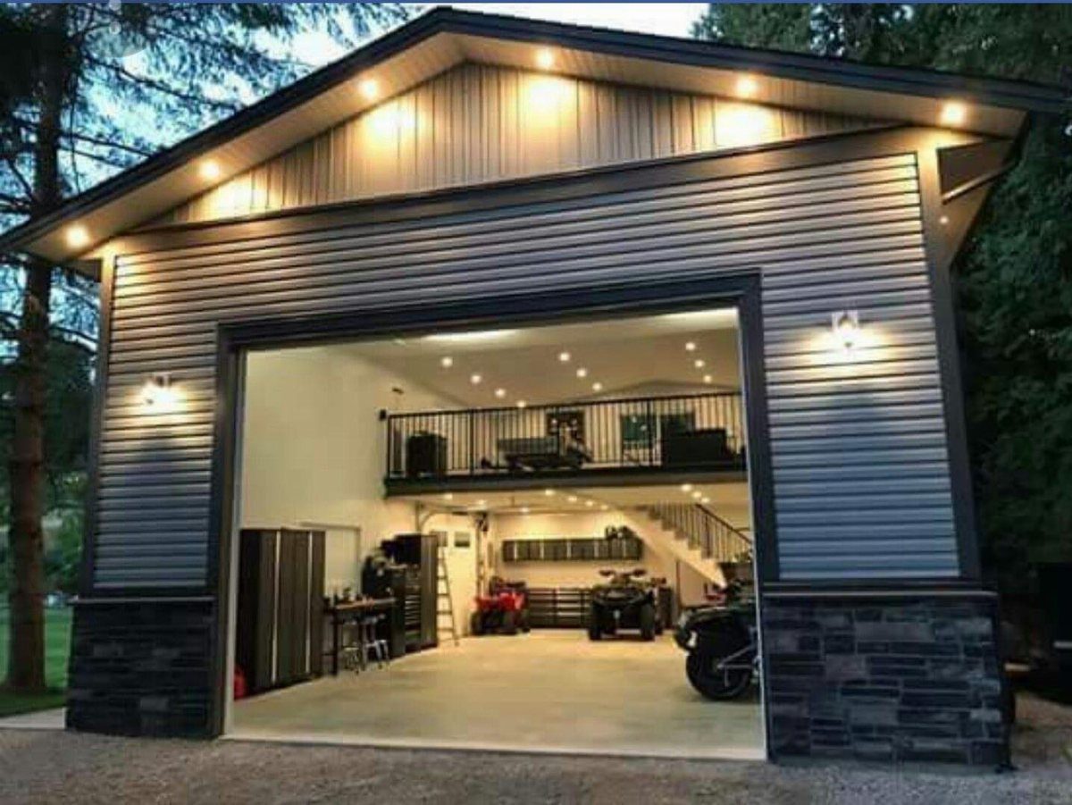 A large two-story metal garage with an open bay showing a mezzanine living area and storage.