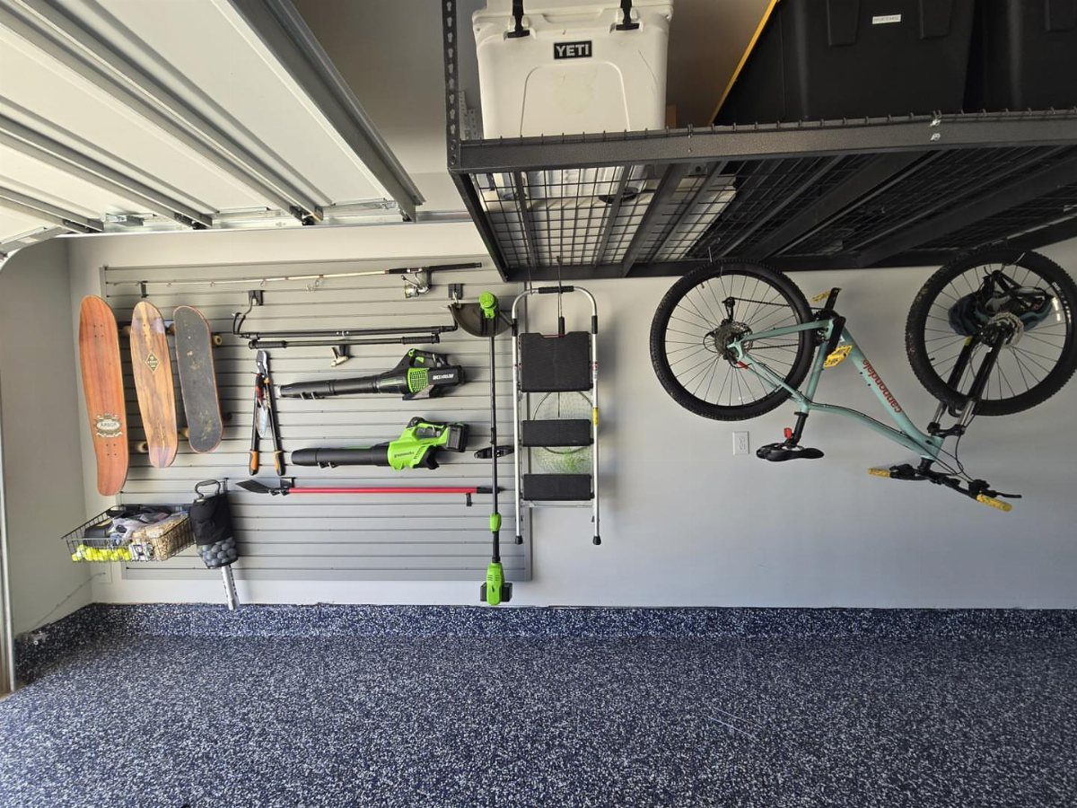 Organized garage with slatwall tool storage, a mounted bicycle, and overhead metal storage racks.