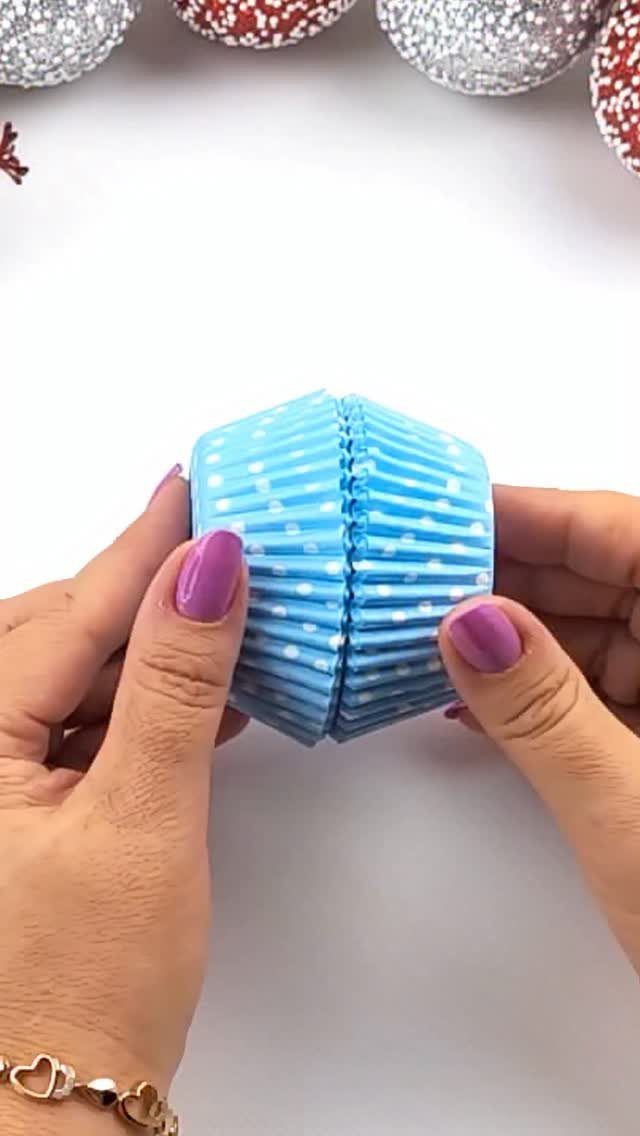Glitter DIY Ornaments to Make 5 Ways 4 Hands holding a blue polka dot cupcake liner folded to hold a round ornament.