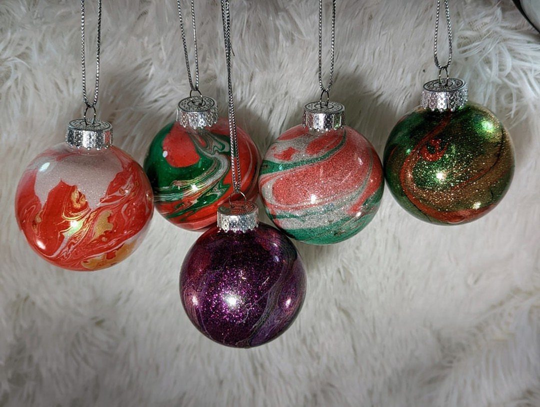 Glitter DIY Ornaments to Make 5 Ways 5 Five colorful glitter ornaments with swirling patterns hanging against a white fuzzy background.