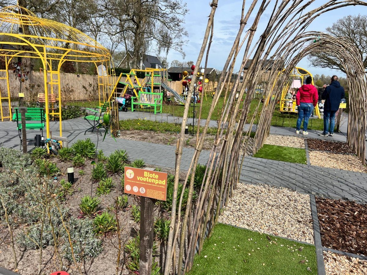 A sensory garden path with various textures like gravel and wood chips under a twig archway.