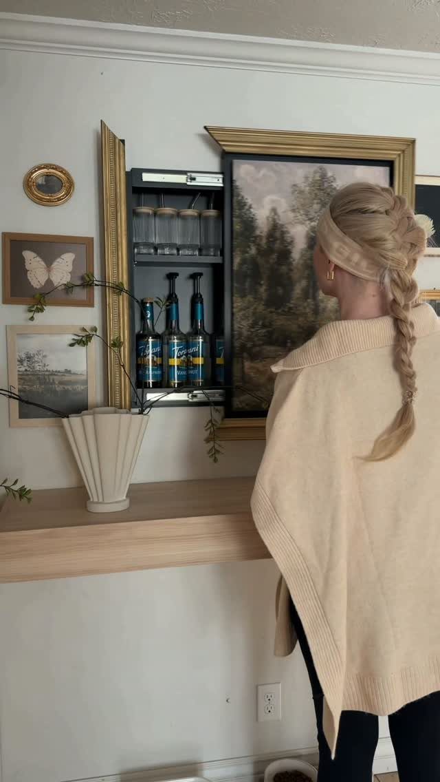 Hidden Storage for Picture Frame: 5 Smart DIY Projects 1 A woman looks at a large landscape painting that opens to reveal hidden bottle storage.