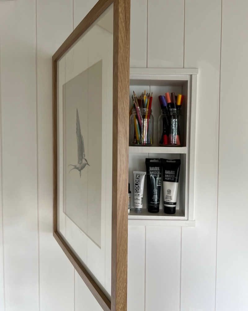 Hidden Storage for Picture Frame: 5 Smart DIY Projects 2 A wooden picture frame opened to reveal a white shadow box filled with art supplies.