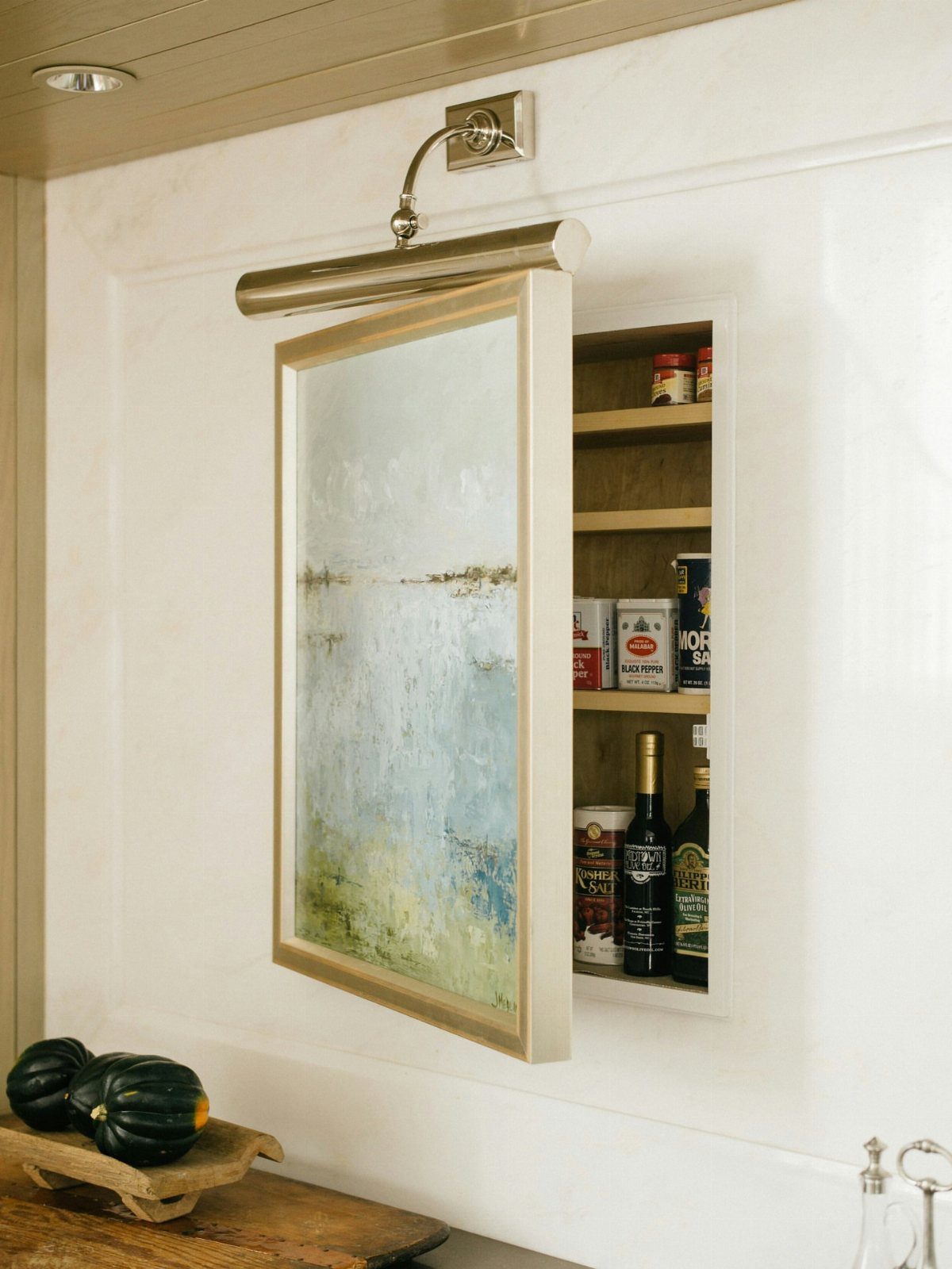 Hidden Storage for Picture Frame: 5 Smart DIY Projects 3 A framed landscape painting on a white wall opens to reveal a hidden pantry shelf.