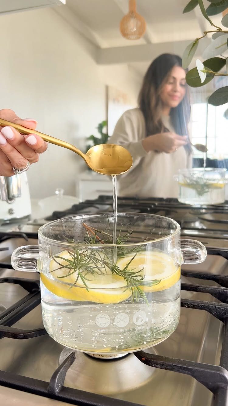 How to Deep Clean New Apartment: 5 Room-by-Room Moves 4 A gold spoon pours liquid into a glass pot with lemon and rosemary on a stove.