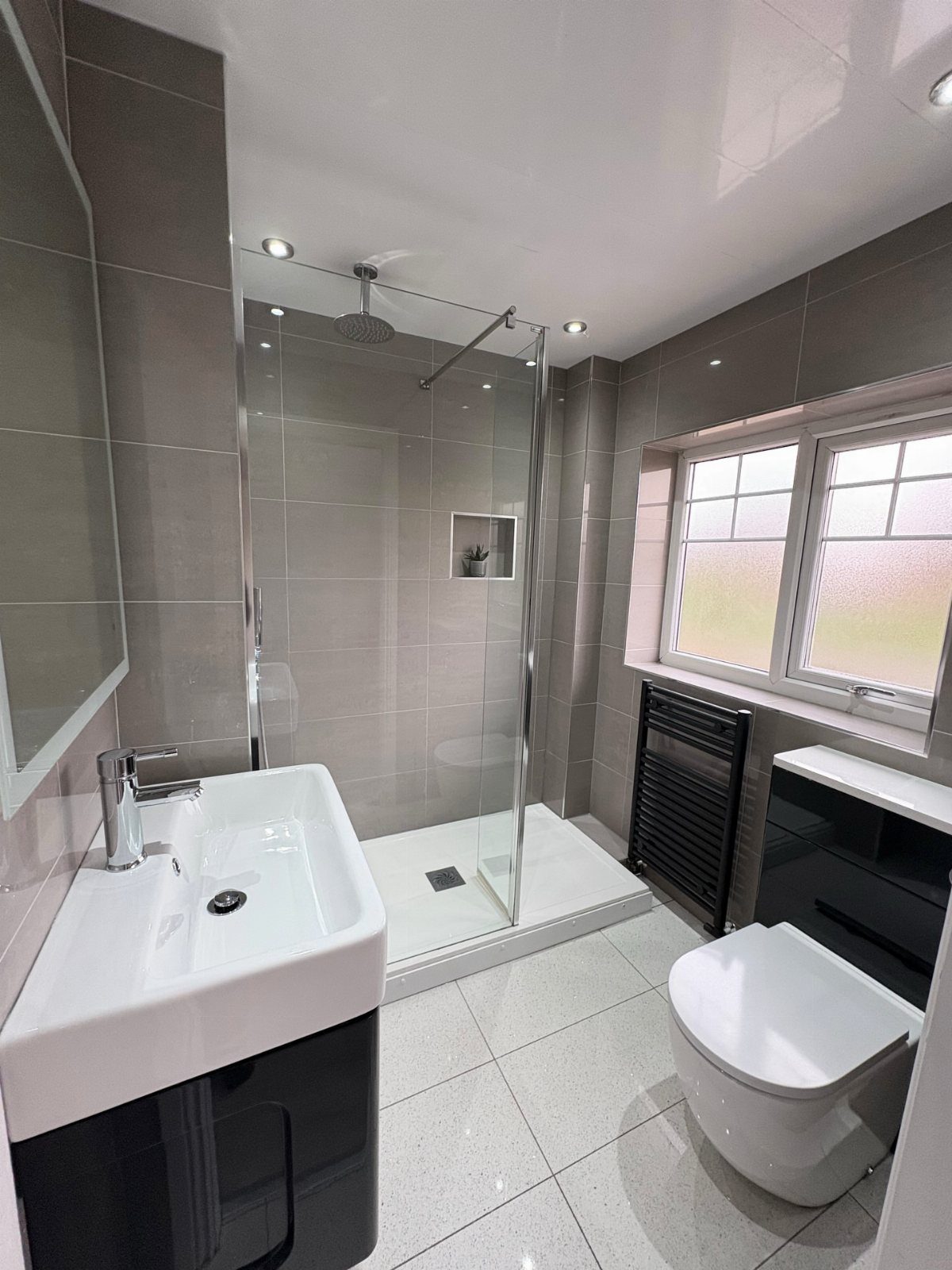How to Deep Clean New Apartment: 5 Room-by-Room Moves 1 A modern bathroom with grey tiles, a glass shower, white sink, and toilet.