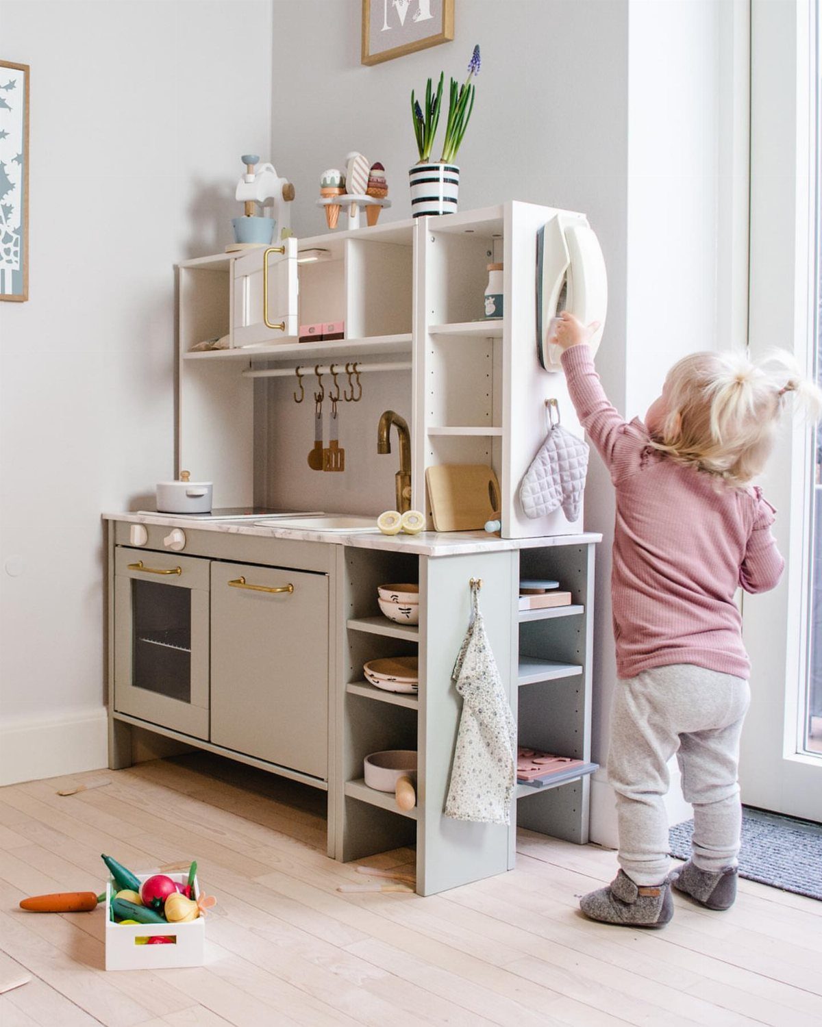 6 IKEA Kids Furniture Hacks for Better Bedrooms 3 A young child playing with a customized grey and white wooden toy play kitchen.