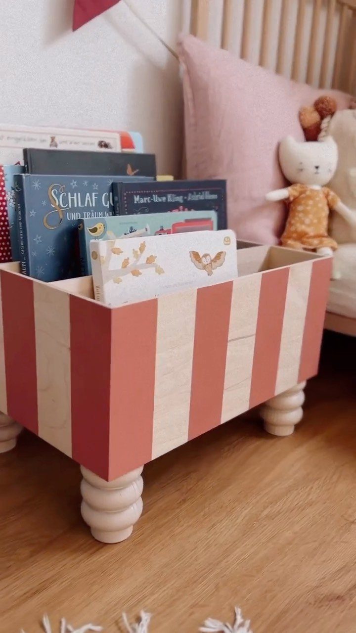 6 IKEA Kids Furniture Hacks for Better Bedrooms 6 Striped pink and white wooden book box filled with children's books on a wooden floor.
