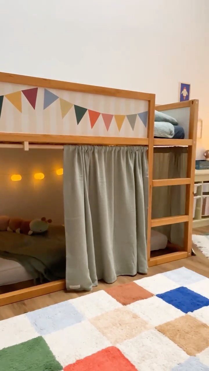 6 IKEA Kids Furniture Hacks for Better Bedrooms 2 Wooden loft bed with grey curtains, colorful bunting, and a checkered rug in a child's room.
