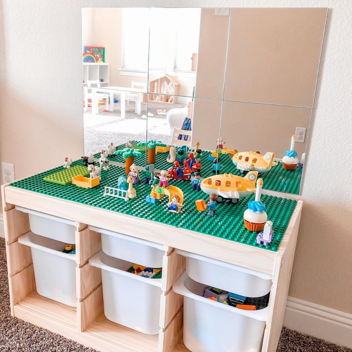6 IKEA Kids Furniture Hacks for Better Bedrooms 4 A wooden storage unit topped with a green LEGO baseplate and various colorful LEGO constructions.