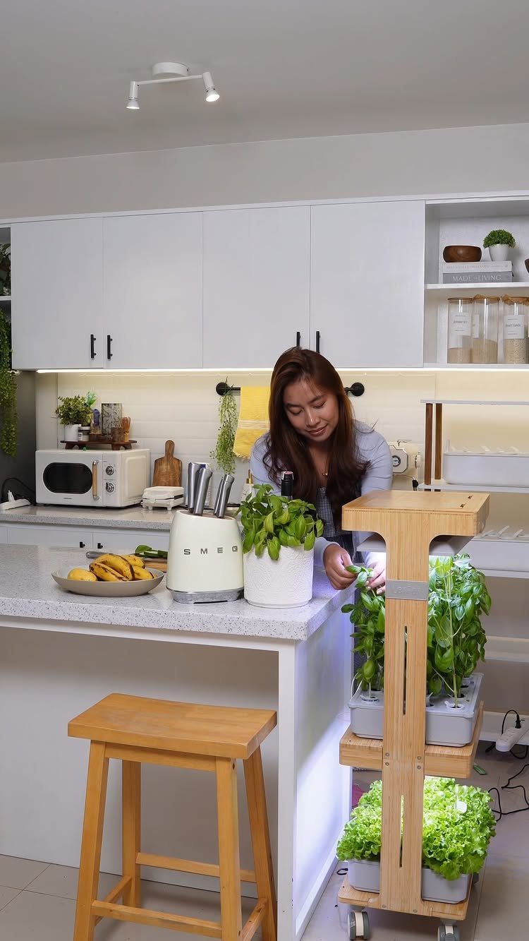 A woman tending to green plants in a multi-tiered wooden indoor hydroponic garden system.