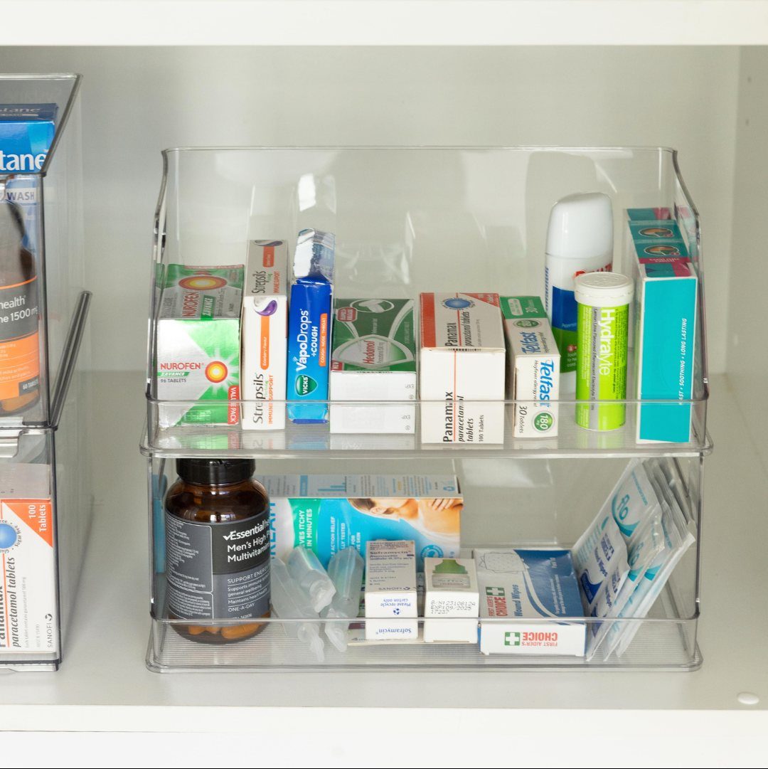 Medicine Cabinet Organization: 5 Fixes to Try in 2026 1 Clear acrylic stackable bins containing various medicine boxes and bottles on a white shelf.