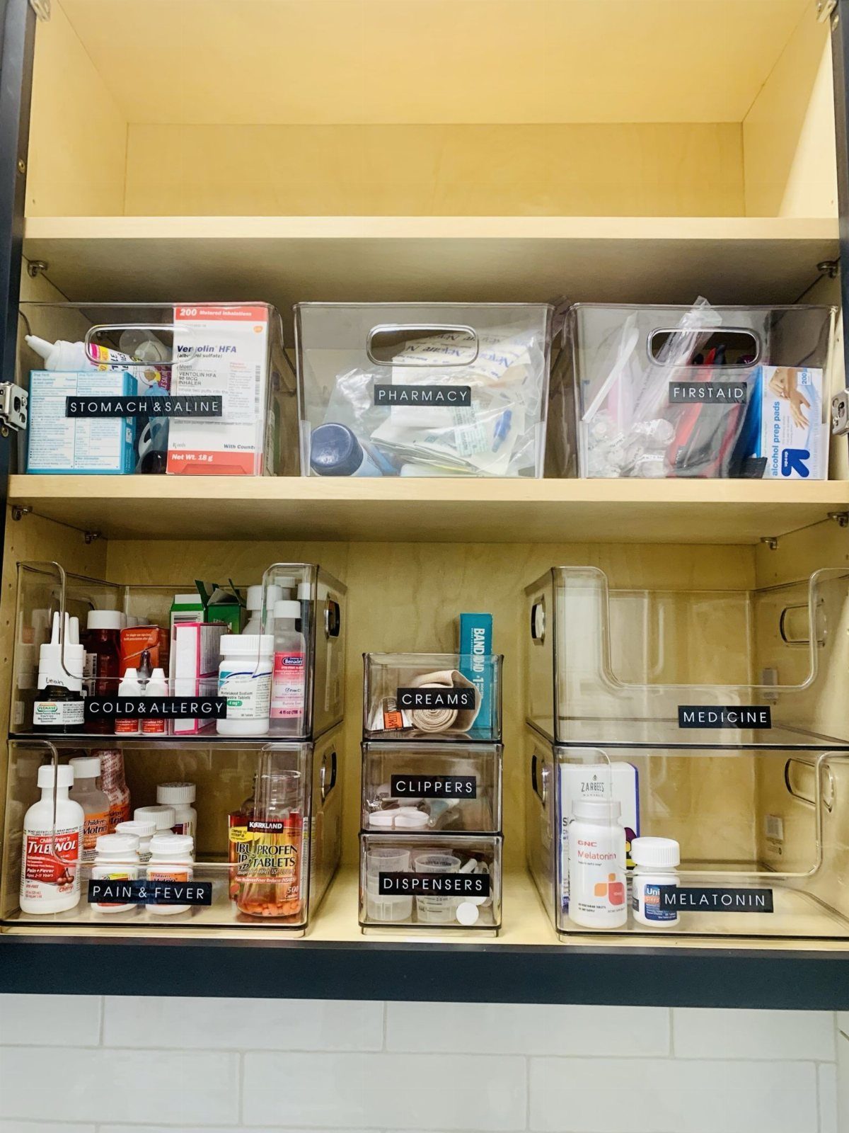 Medicine Cabinet Organization: 5 Fixes to Try in 2026 2 Clear acrylic bins and stackable drawers organized with labeled medical supplies inside a wooden cabinet.