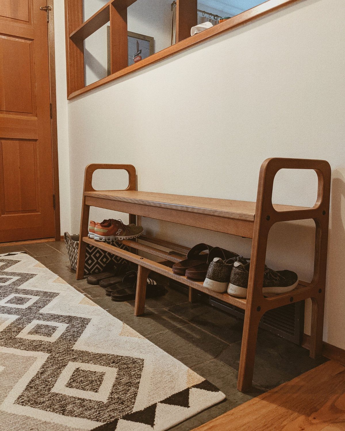 Mid Century Modern Entryway Bench With Storage: 8 Ideas 4 A wooden mid-century modern entryway bench with two shelves holding several pairs of shoes.