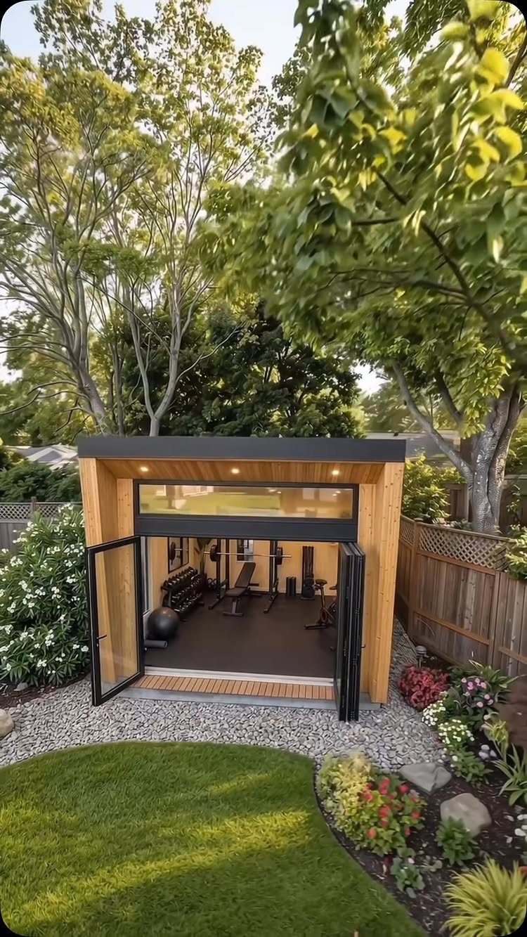 7 Modern Shed Ideas for Compact Yards, Studios & Integrated Outdoor Living 2 Modern wooden backyard studio with open glass doors revealing a home gym interior.