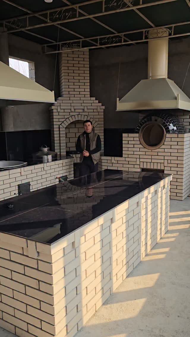 Outdoor Kitchen No Grill: 8 Ideas for Cooking Outside 3 A man standing behind a long brick outdoor kitchen counter with dark granite tops.