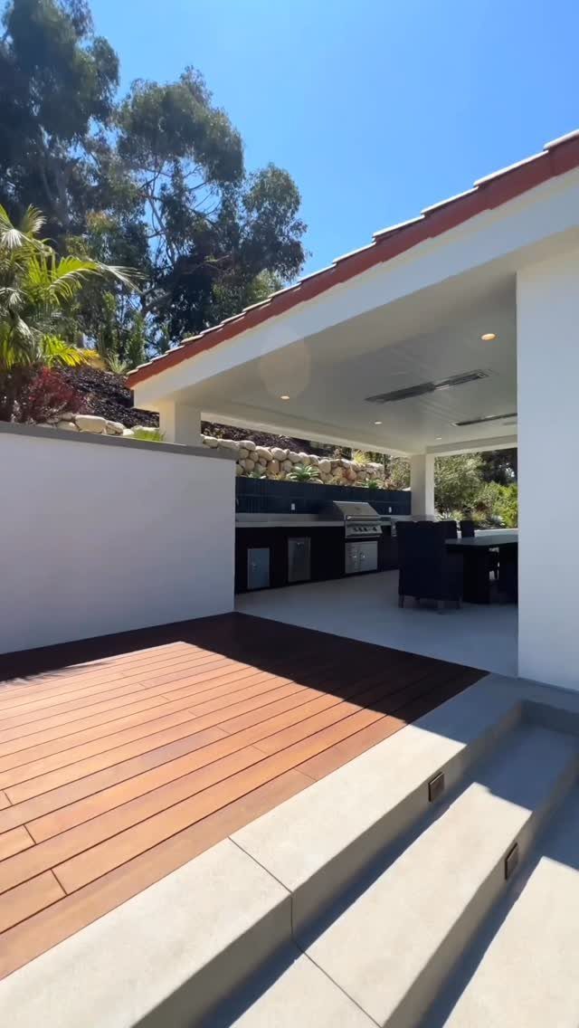 7 Outdoor Patio Kitchen Ideas for Every Backyard Style 4 A modern outdoor kitchen with dark cabinets and a grill under a white covered patio.