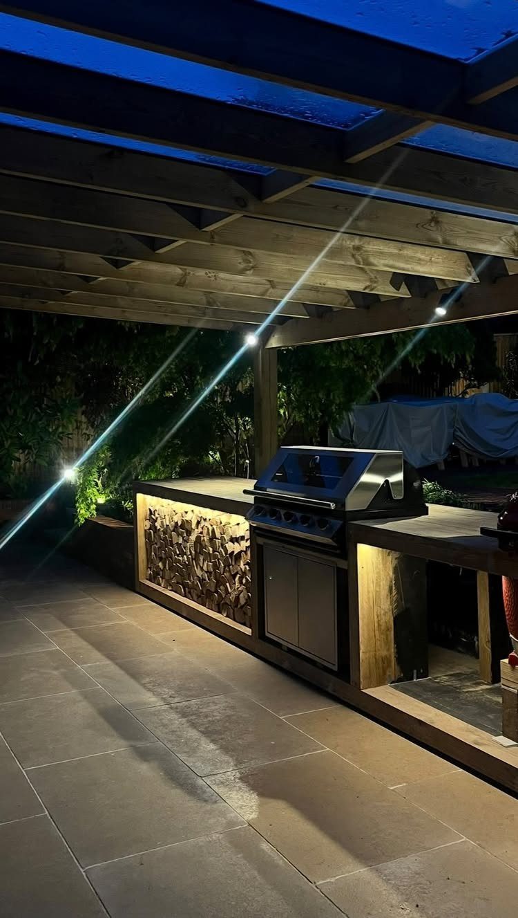 7 Outdoor Patio Kitchen Ideas for Every Backyard Style 7 Outdoor kitchen with a stainless steel grill and warm integrated lighting under a wooden pergola.