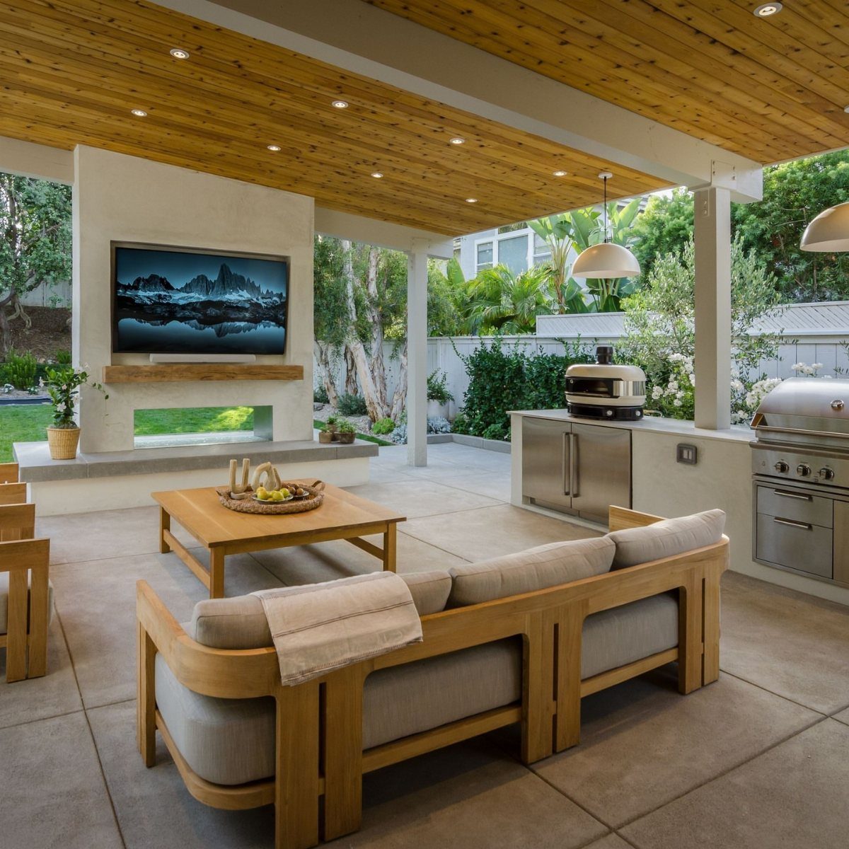 7 Outdoor Patio Kitchen Ideas for Every Backyard Style 2 Modern covered patio with outdoor kitchen, large television, and comfortable wooden lounge seating.