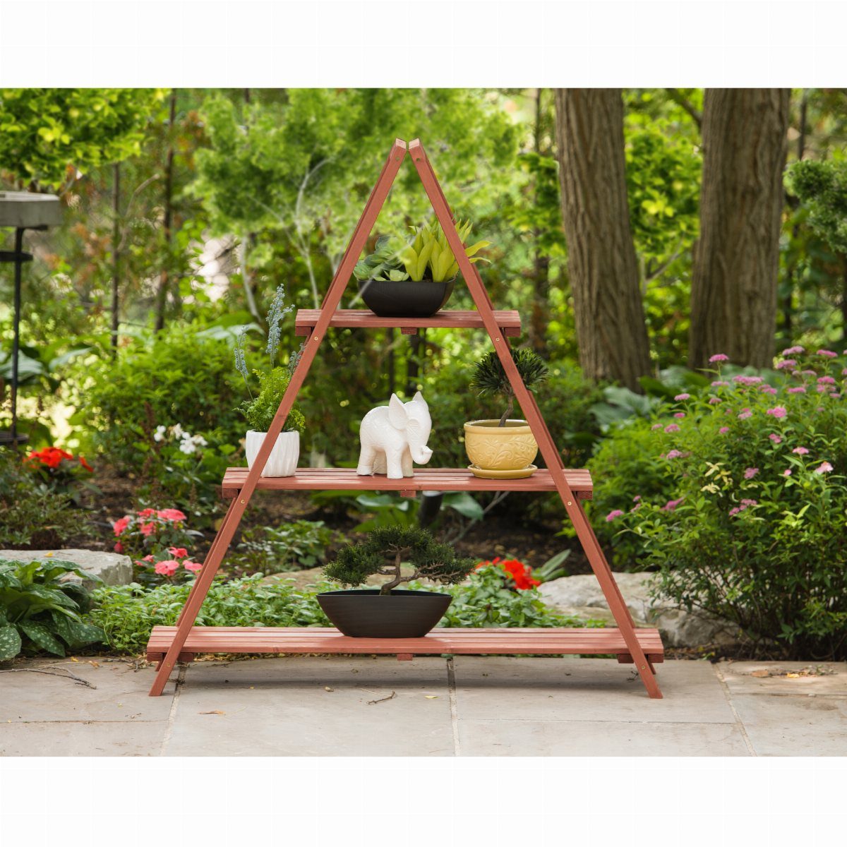 A reddish-brown wooden ladder plant stand holding various potted plants on a stone patio.