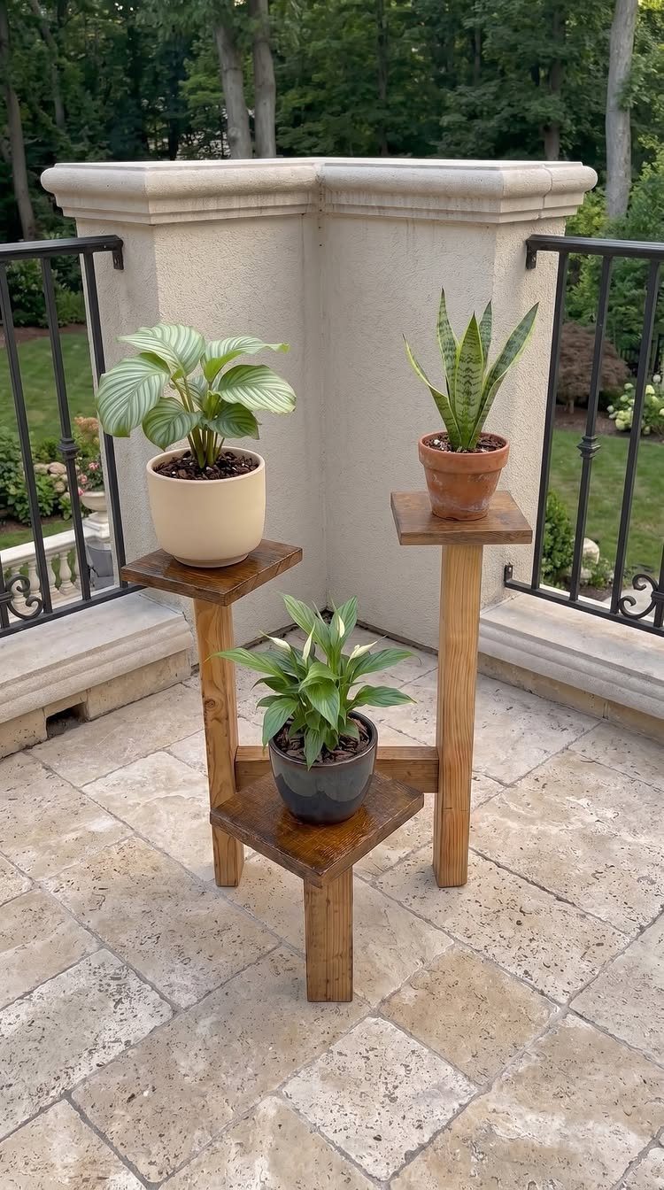 A three-tiered wooden plant stand holding various potted green plants on a stone patio.