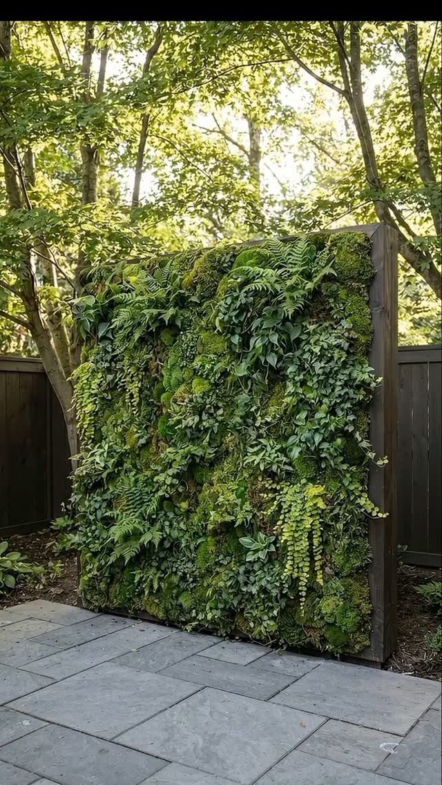 A dense vertical garden wall with green ferns and moss on a wooden frame.