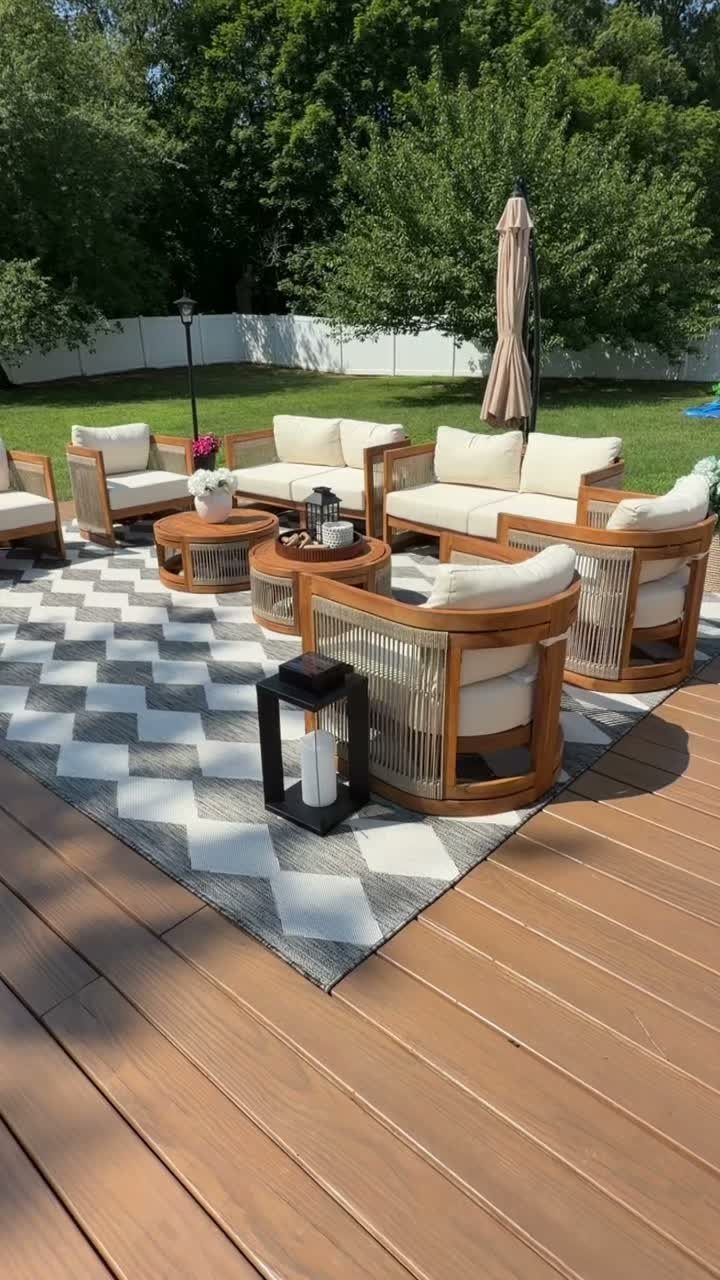 28 Outdoor Wooden Deck Ideas for Any Yard Size 11 Wicker outdoor furniture set with cream cushions arranged on a patterned rug over a wooden deck.