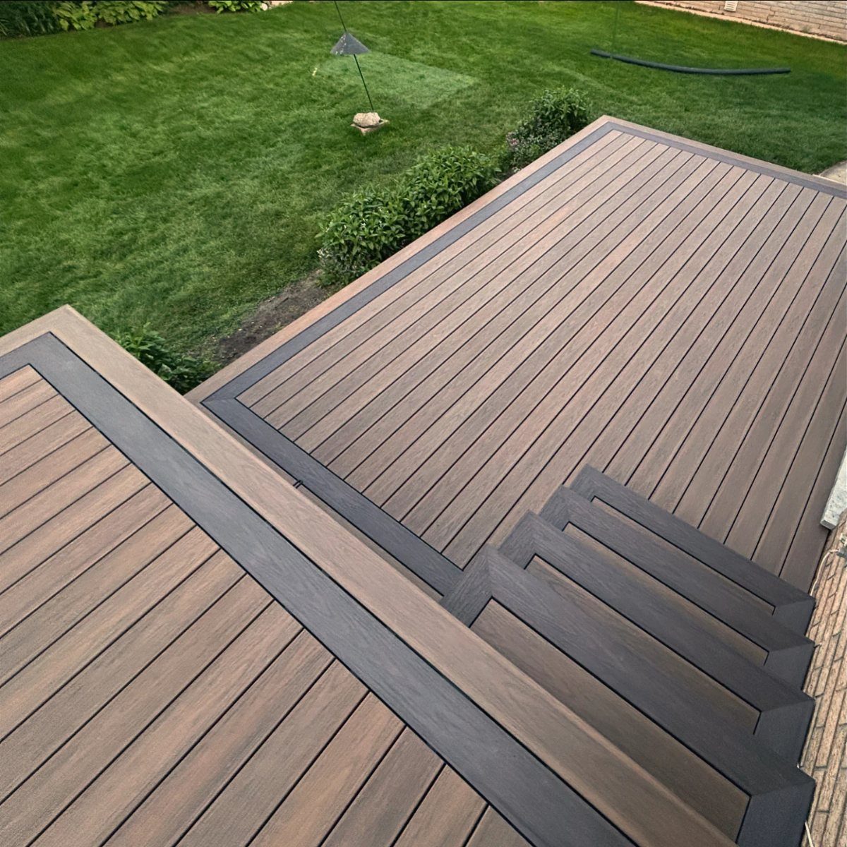 28 Outdoor Wooden Deck Ideas for Any Yard Size 12 Two-tone wooden deck with light brown planks and dark grey geometric borders.