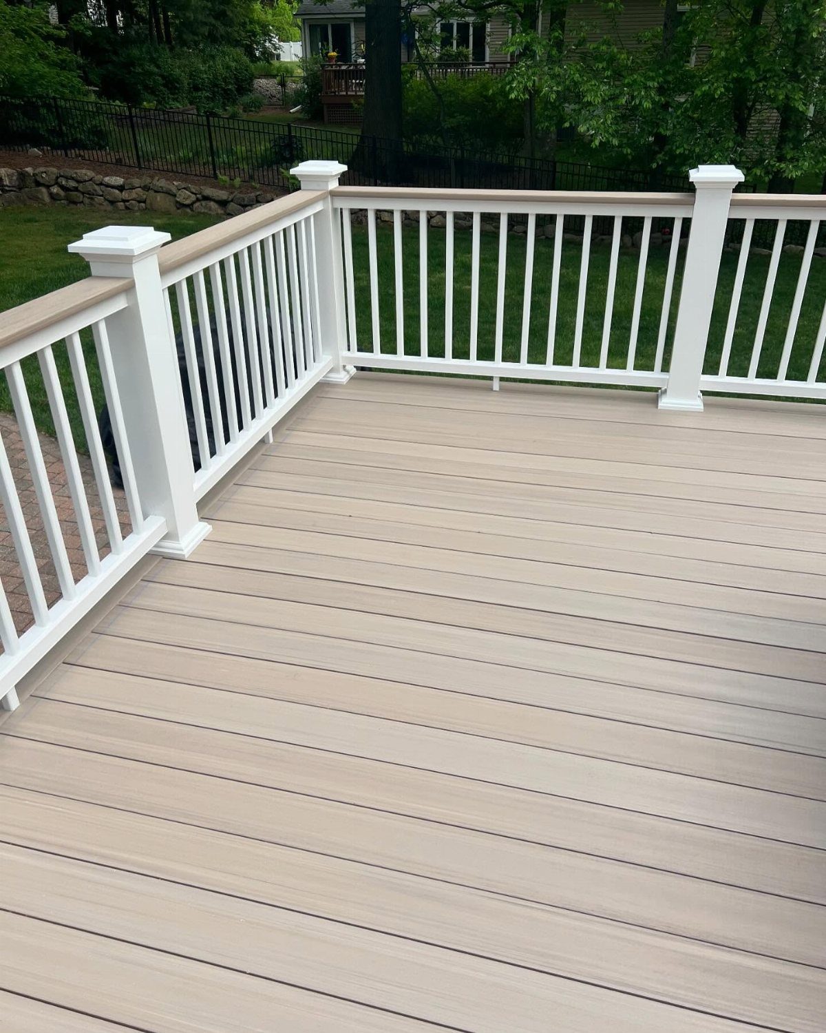 28 Outdoor Wooden Deck Ideas for Any Yard Size 4 Light grey composite decking with white railings overlooking a lush green backyard area.
