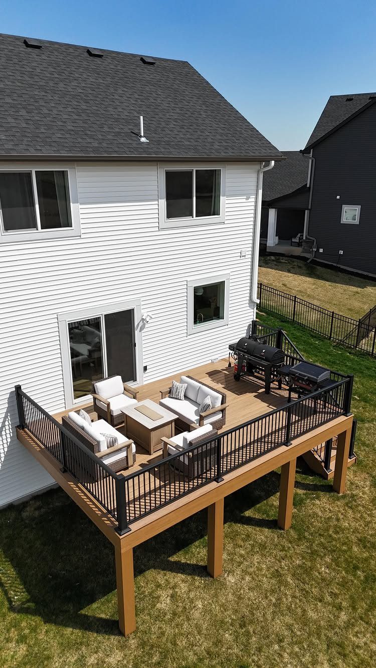 20 Patio and Deck Ideas to Make Your Yard Feel Like a Room 14 A modern wooden deck with white outdoor furniture and a black grill attached to a white house.