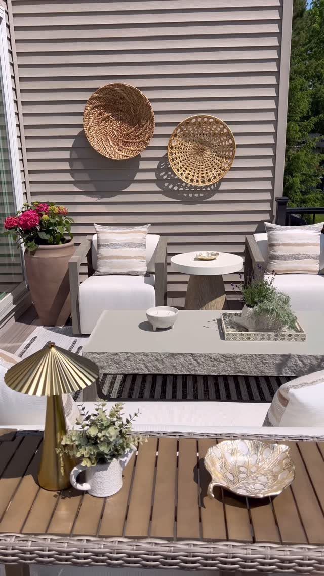 20 Patio and Deck Ideas to Make Your Yard Feel Like a Room 10 Woven baskets hang on a grey wall above a patio with white chairs and stone tables.