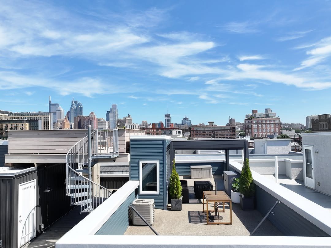 20 Patio and Deck Ideas to Make Your Yard Feel Like a Room 11 A modern rooftop deck with outdoor furniture and potted plants overlooking a city skyline.