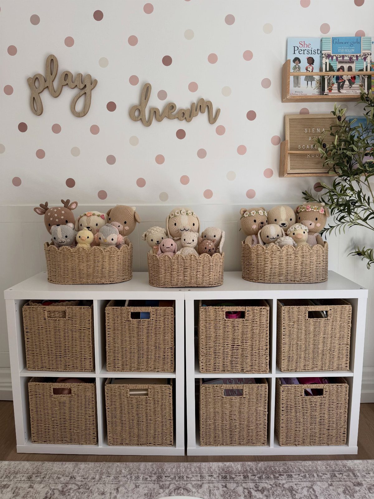Woven seagrass baskets filled with stuffed animals sitting on a white cubby storage unit.