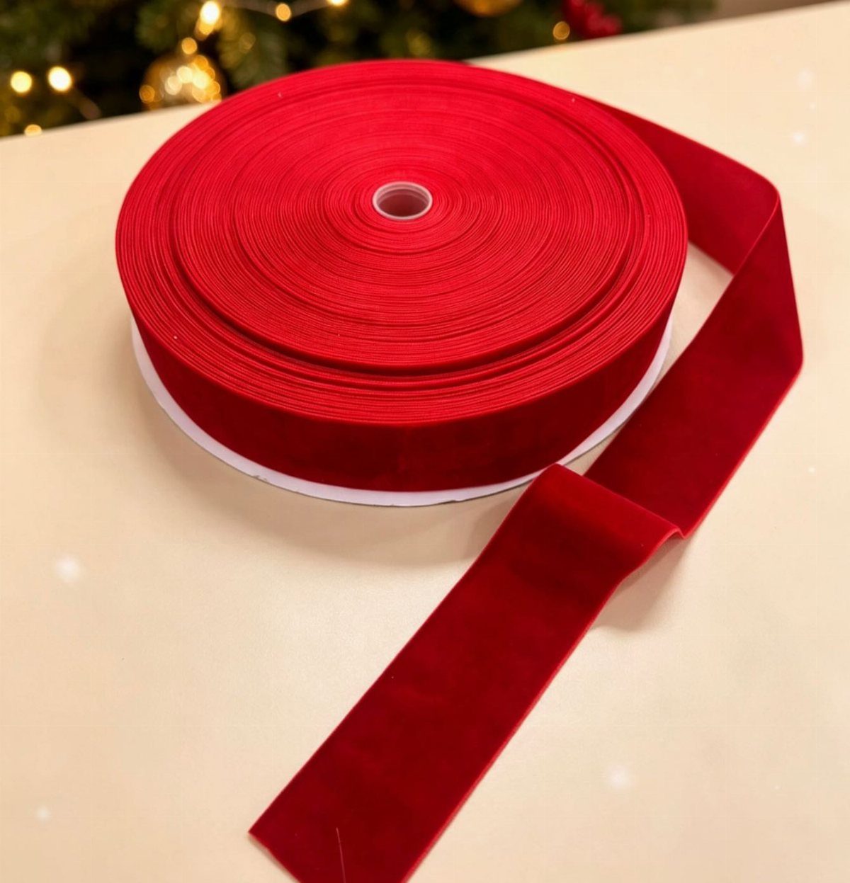 8 Red and Green Christmas Tree Ideas 4 A large roll of wide red velvet ribbon on a light surface with Christmas lights.