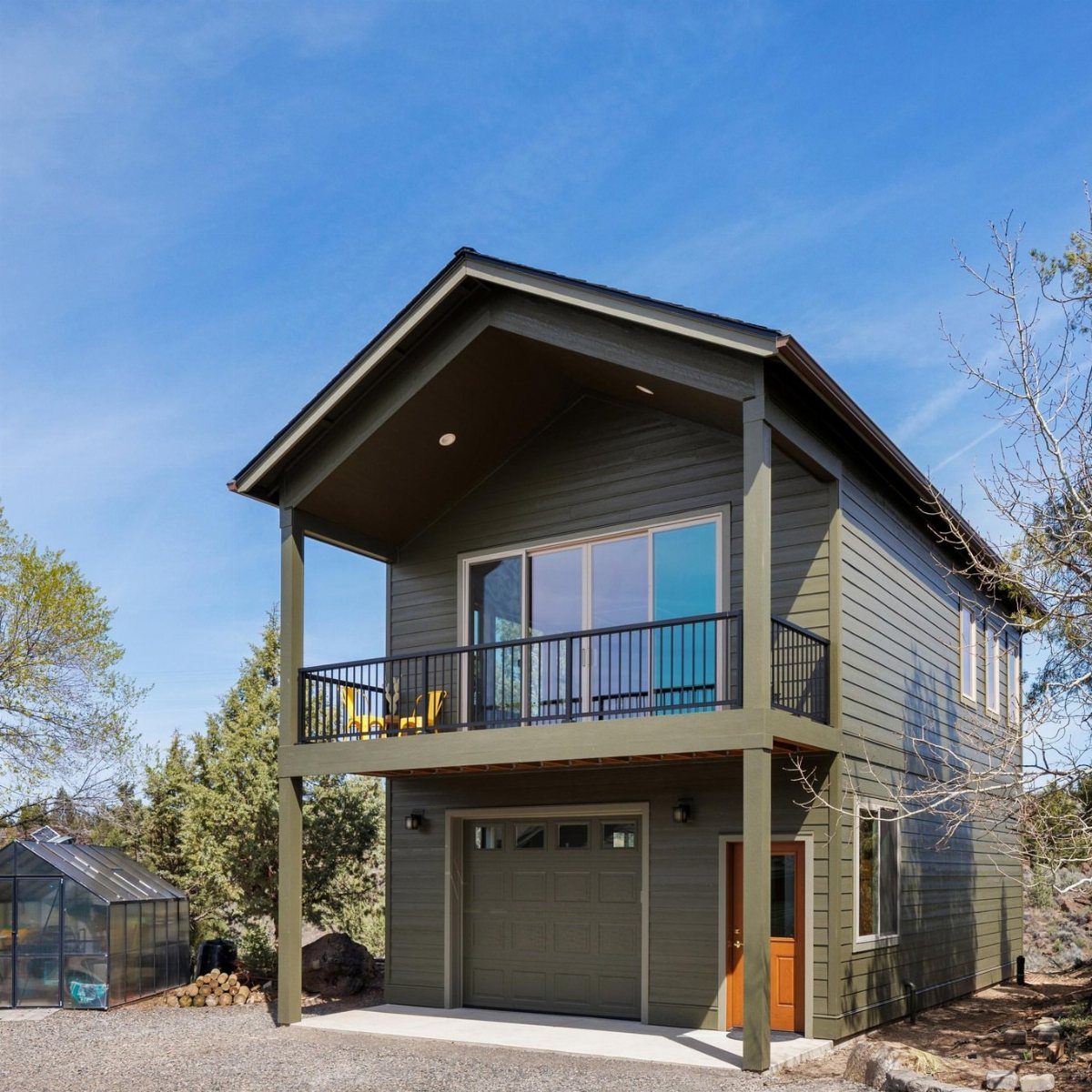 5 Room on Top of Garage Ideas for Extra Living Space 3 A two-story olive green building with a garage below and a balcony above.