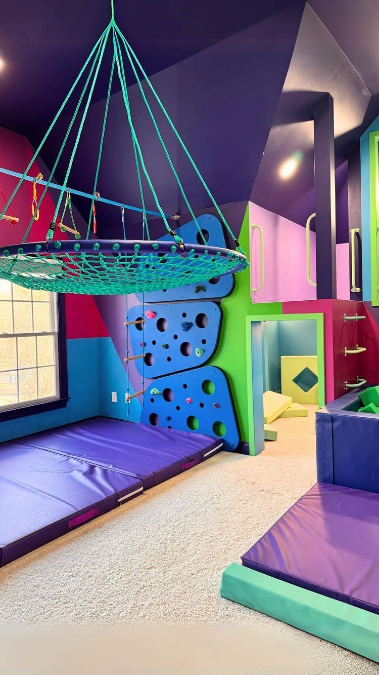 5 Room on Top of Garage Ideas for Extra Living Space 1 A vibrant children's playroom with climbing walls, hanging nets, and colorful padded floor mats.