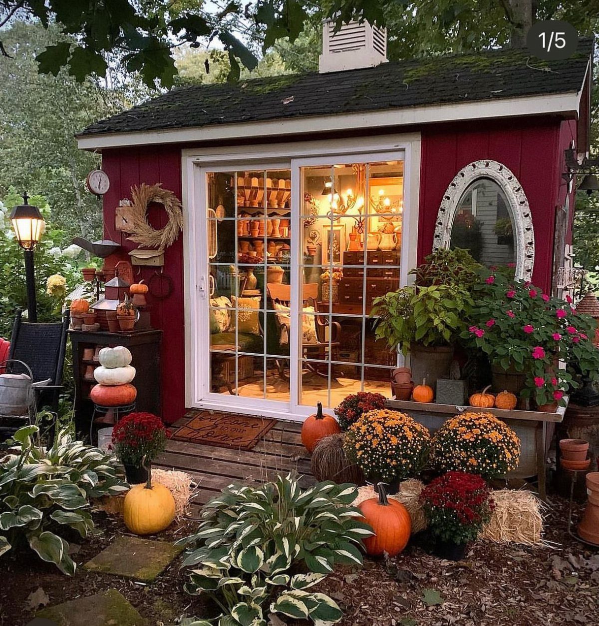 10 Shed Colors Ideas to Paint Your Backyard Storage 7 A red wooden garden shed decorated with pumpkins and autumn flowers in a lush garden.